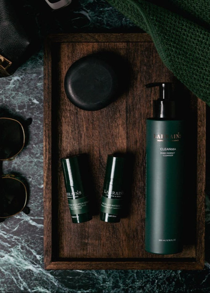 Labrains skincare products on a wooden tray with sunglasses and a watch on a dark marble surface
